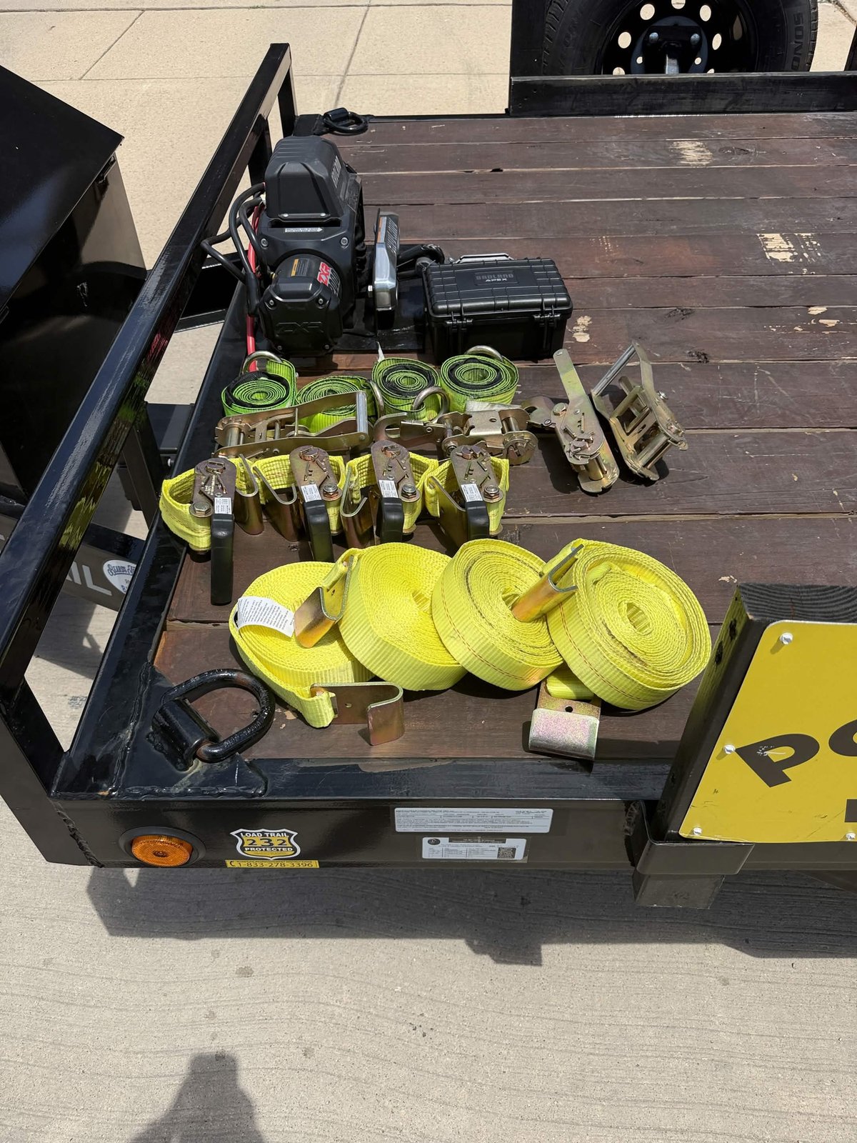 Yellow ratchet straps, spare tire, and winch laid out on car hauler deck